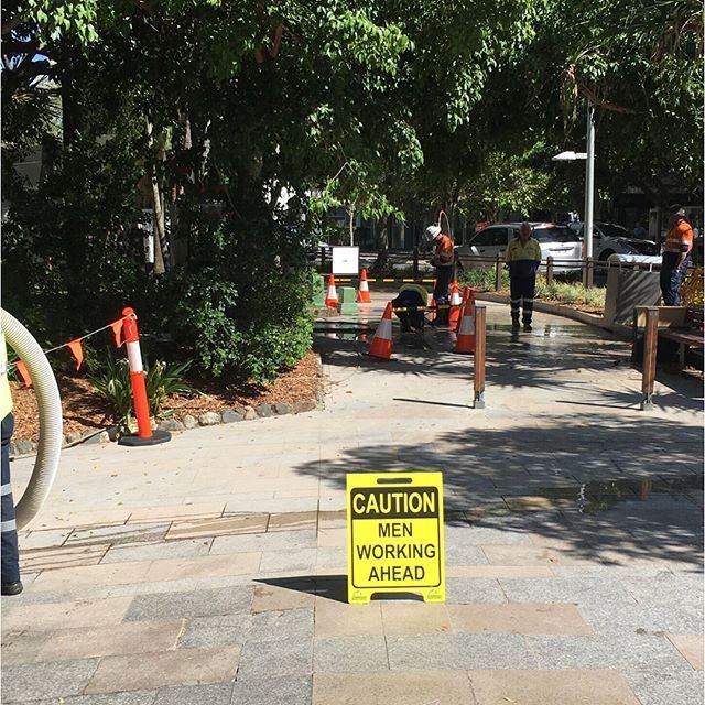 A yellow sign on the sidewalk says caution men working ahead