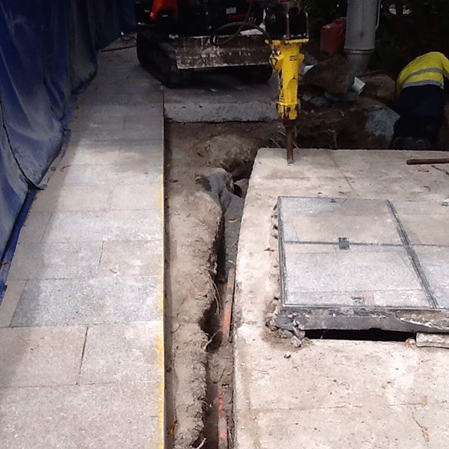 A yellow hammer is being used to dig a hole in the ground