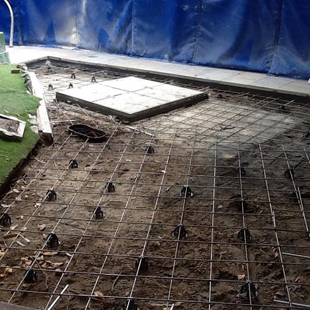 A concrete patio is being built with a blue tarp in the background.
