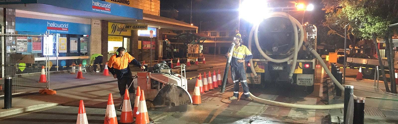 A group of construction workers are working on a street at night.
