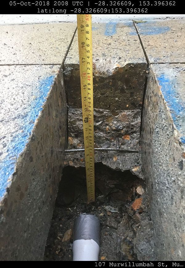 A measuring tape is being used to measure a hole in the ground