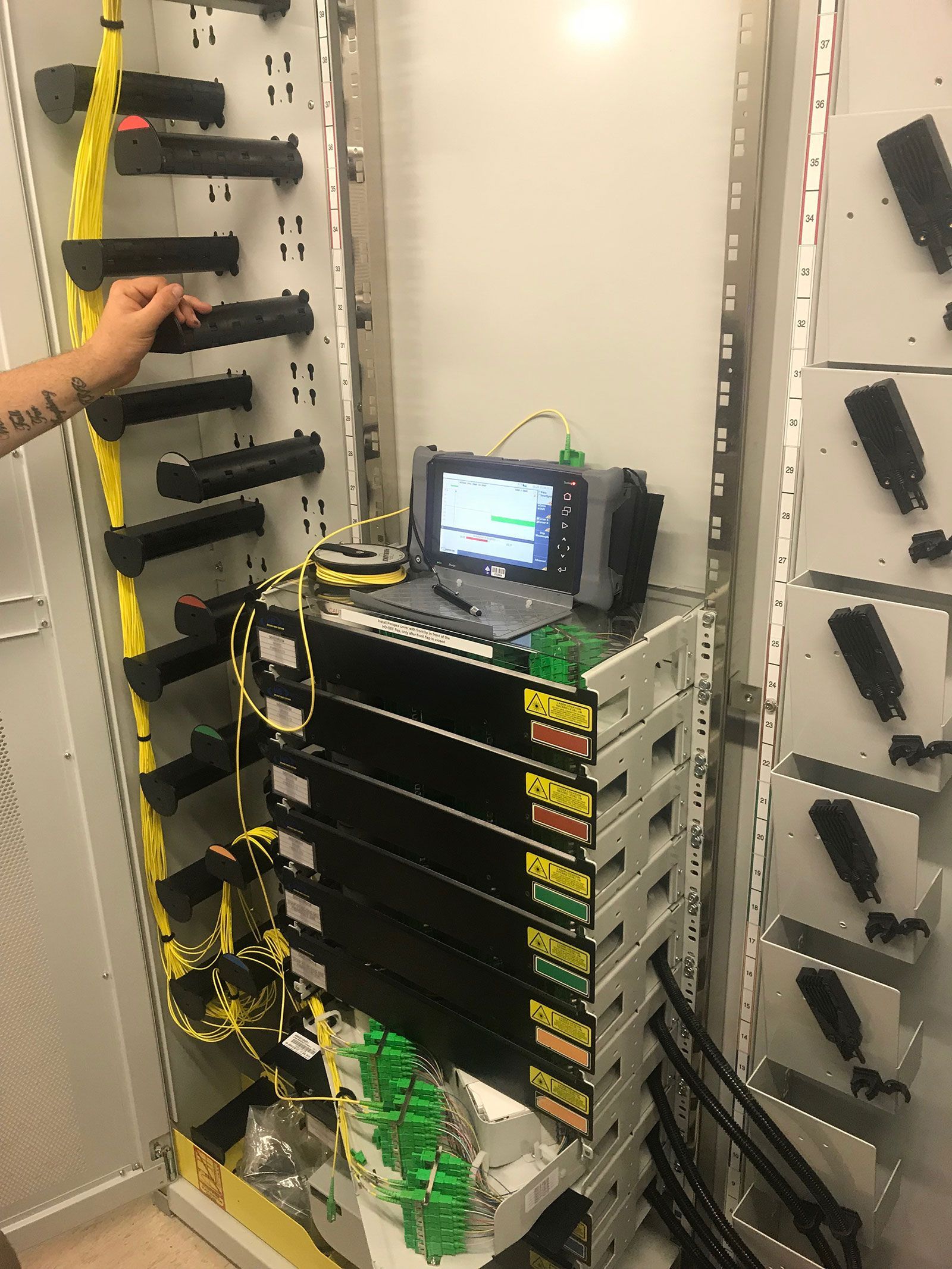 A person is working on a computer in a server room.
