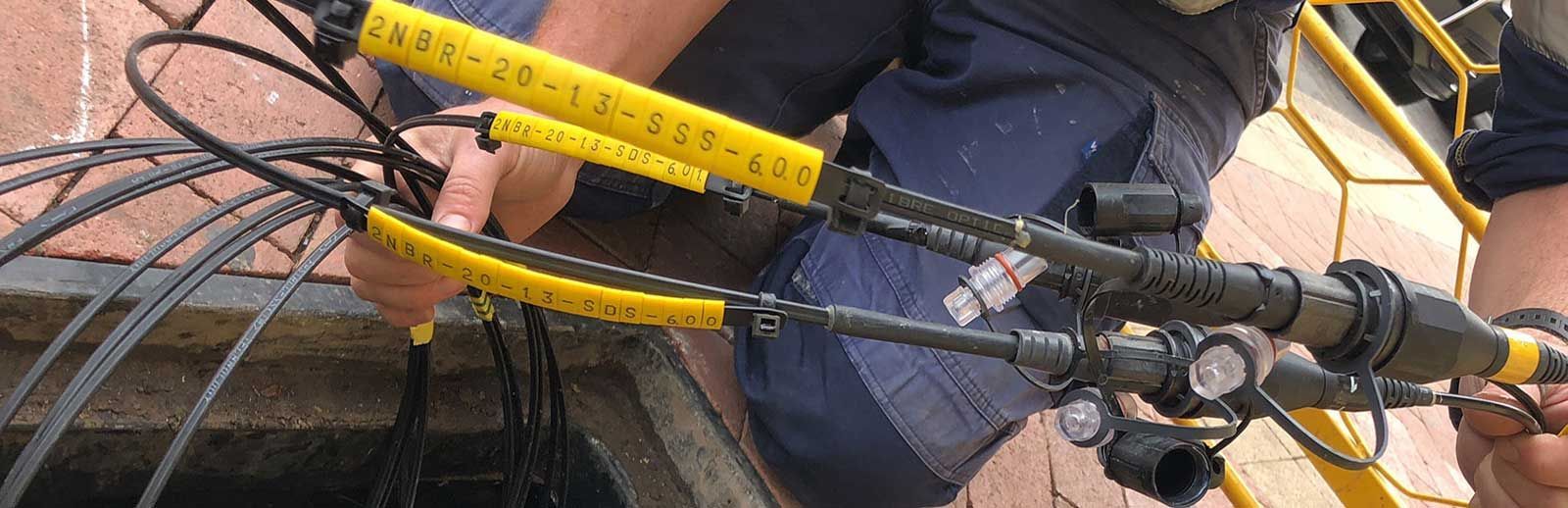 A person is working on a pipe with a yellow tape on it.