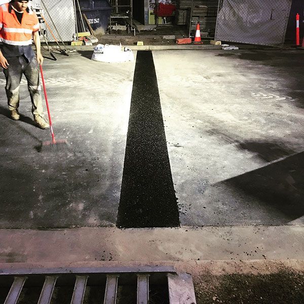 A man with a broom is standing next to a black line on the ground