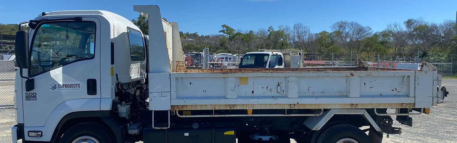 A white dump truck is parked in a gravel lot.