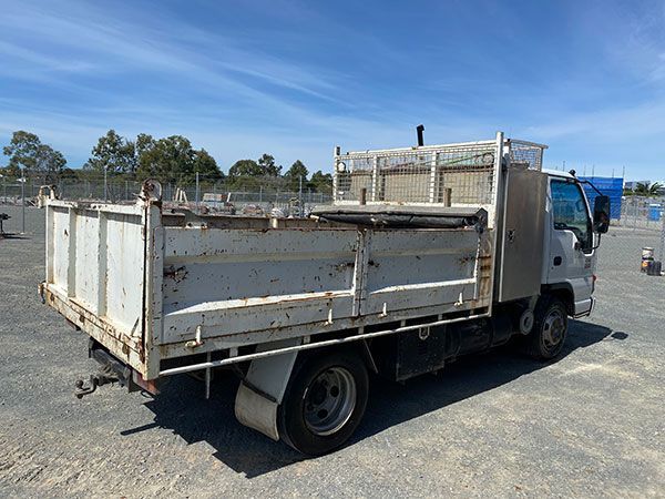 A white dump truck is parked in a dirt lot.