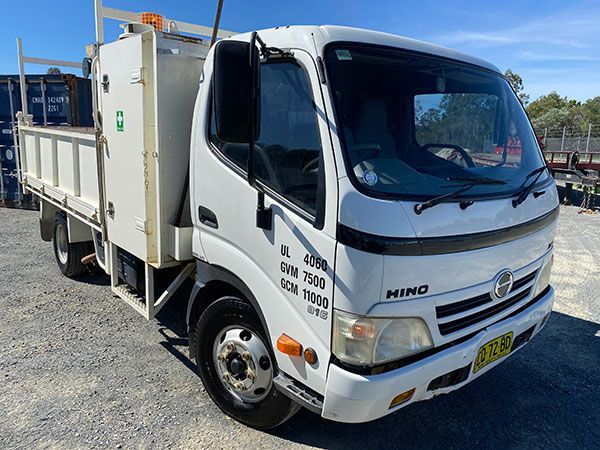 A white hino truck is parked in a gravel lot.