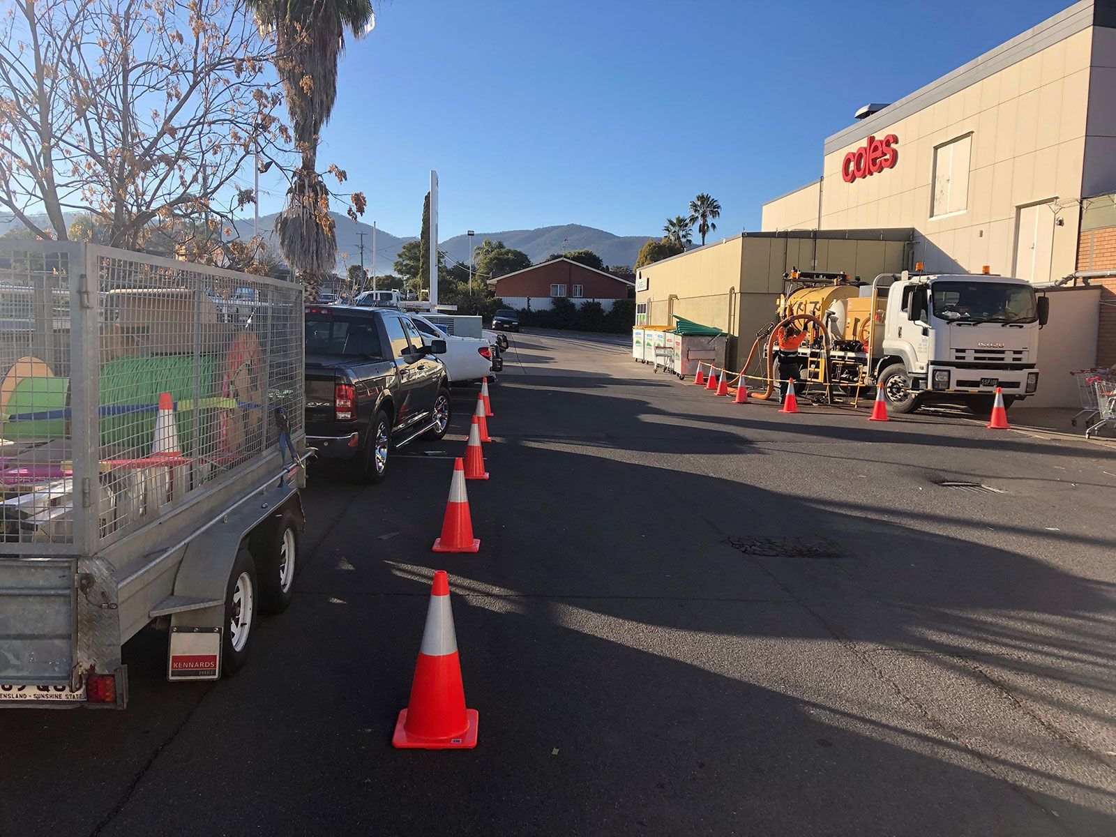A row of orange and white traffic cones are lined up on the side of the road.