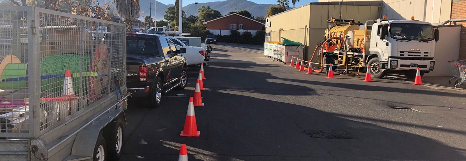 A truck is parked on the side of the road next to a row of traffic cones.