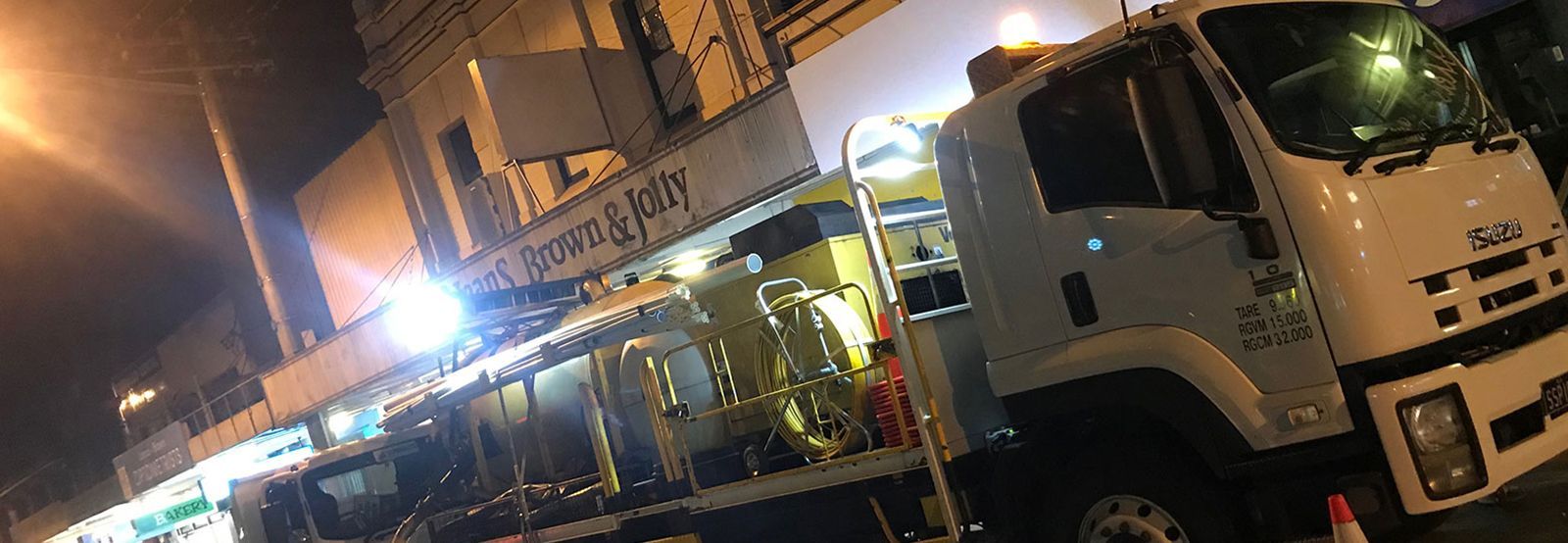 A large white truck is parked in front of a building at night.