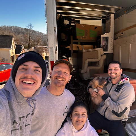 A group of people are posing for a picture in front of a moving truck