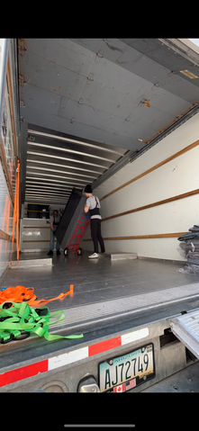 A man is pushing a dolly into a moving truck.