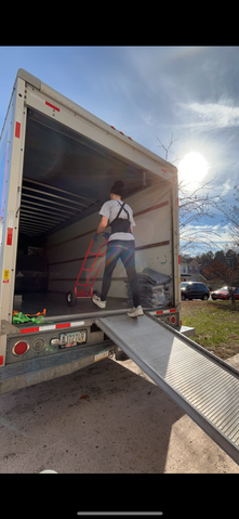 A man is standing on the ramp of a moving truck.