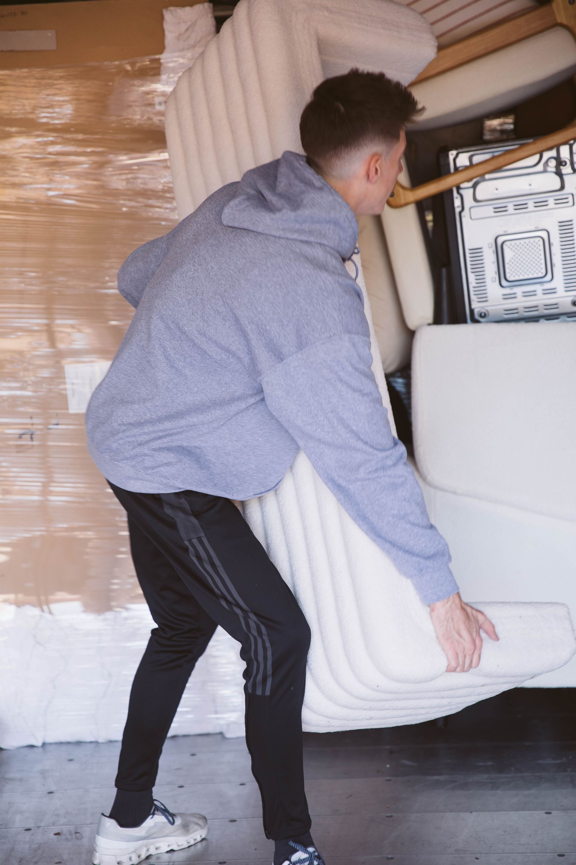A man is carrying a white couch into a truck.