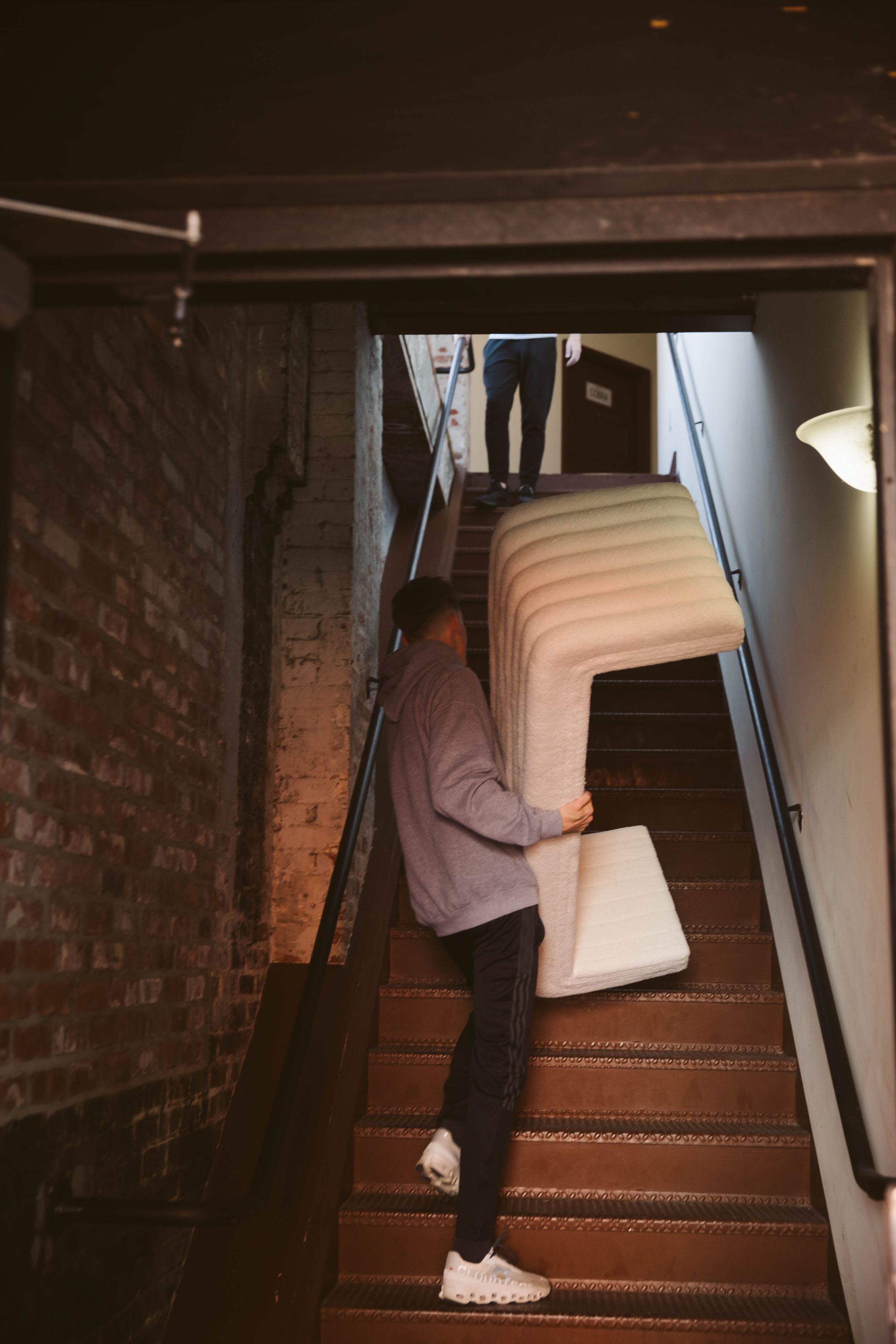 A man is carrying a couch up a set of stairs.