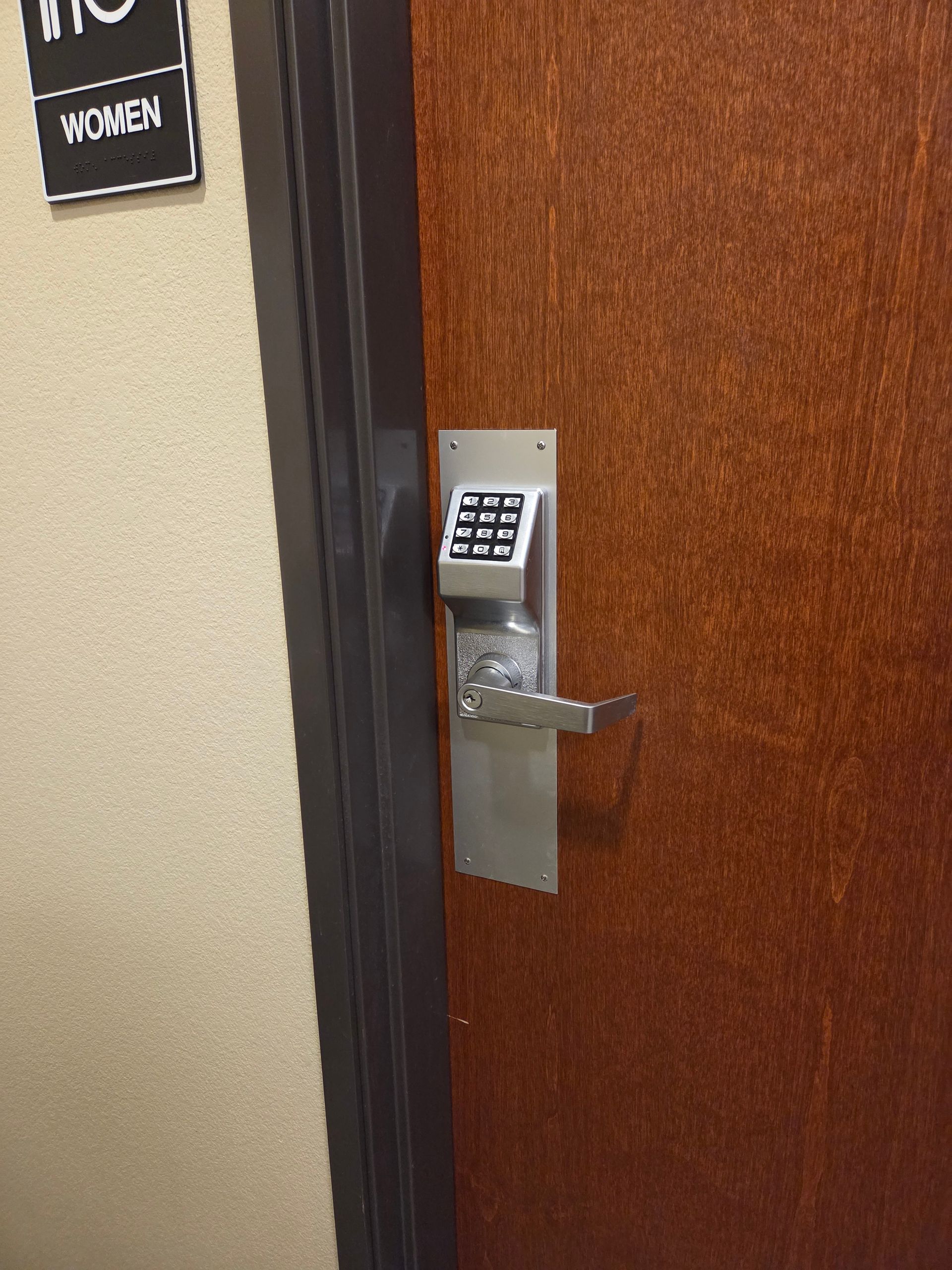 Office door with keypad lock and a women’s restroom sign on the wall