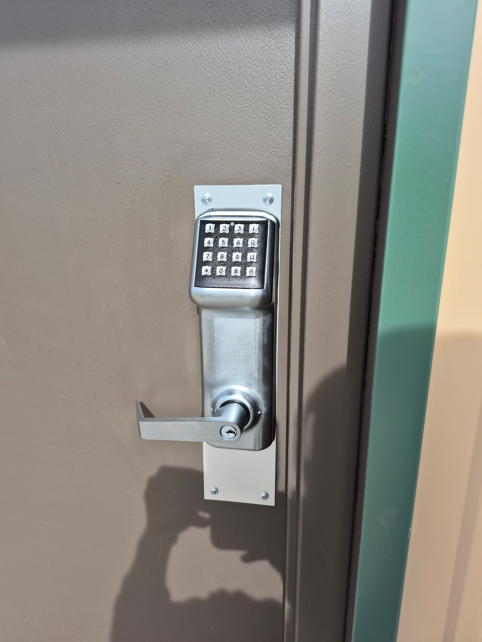 Keypad lock on a brown metal door with a horizontal lever handle