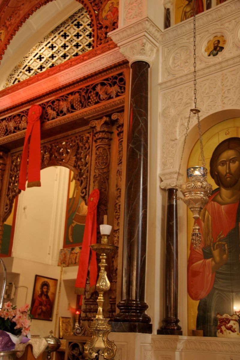 Ornate church altar with red banners, candles, and a large icon of Jesus on the right