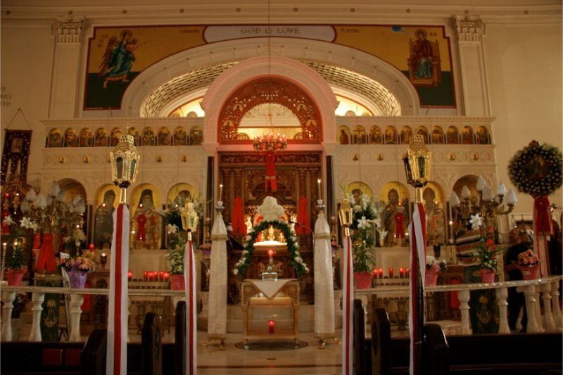 Ornate church altar with gold icons, candles, and a central arched shrine under warm lighting