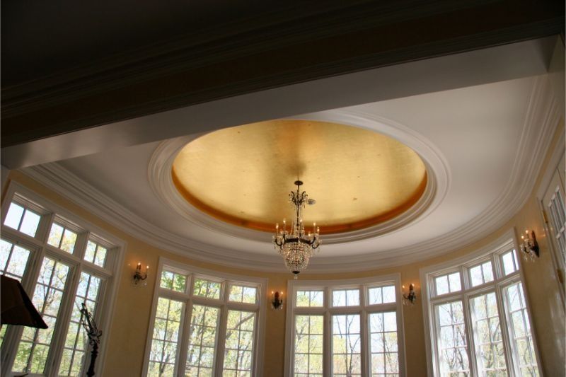 Elegant room ceiling with oval gold dome, chandelier, and tall curved windows