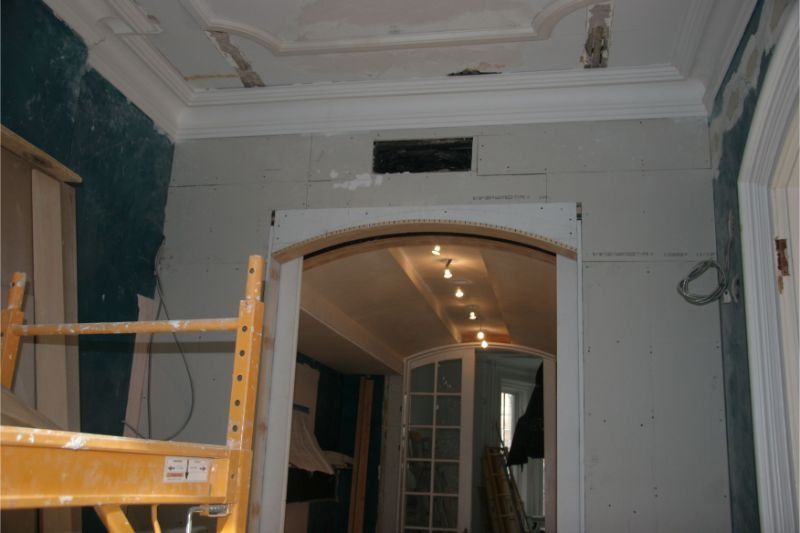Partially renovated room with archway, ladder, and exposed ceiling details