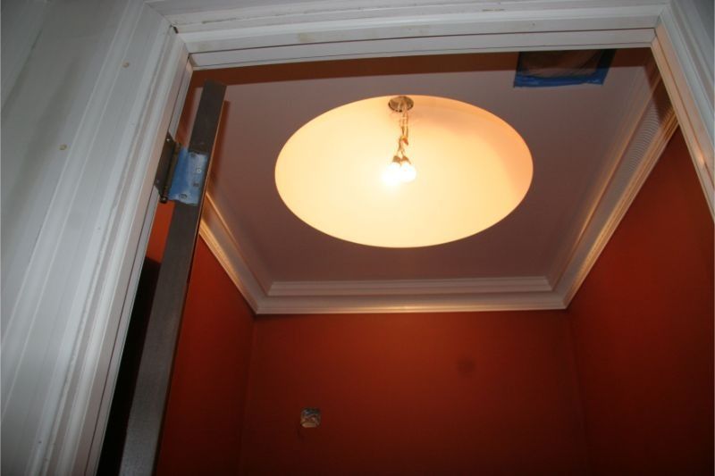 Stairwell ceiling with a lit round light fixture in a red-walled entryway