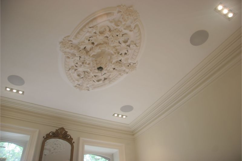 Ceiling with ornate plaster medallion and recessed lights in a cream-colored room