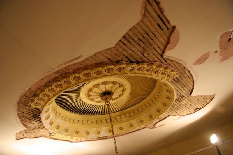 Ornate circular ceiling medallion with gold and tan decorative patterns and hanging light fixture
