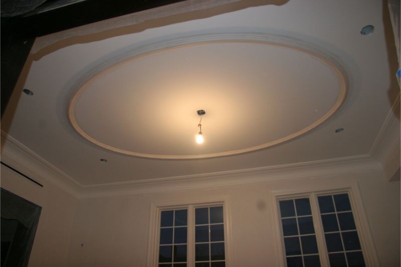 Ceiling with oval recessed design and a single hanging light above two windows