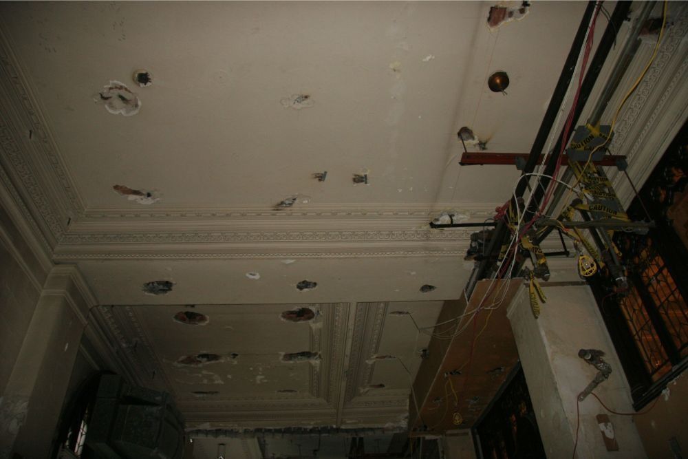 Dim ceiling with many recessed lights and hanging cables in an unfinished interior