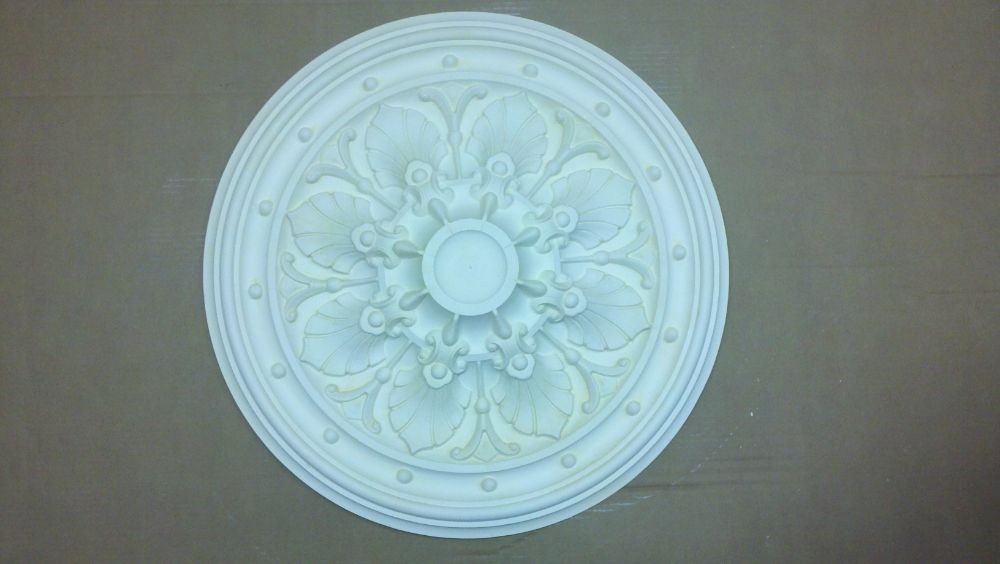 White ornate circular ceiling medallion centered on a beige wall background