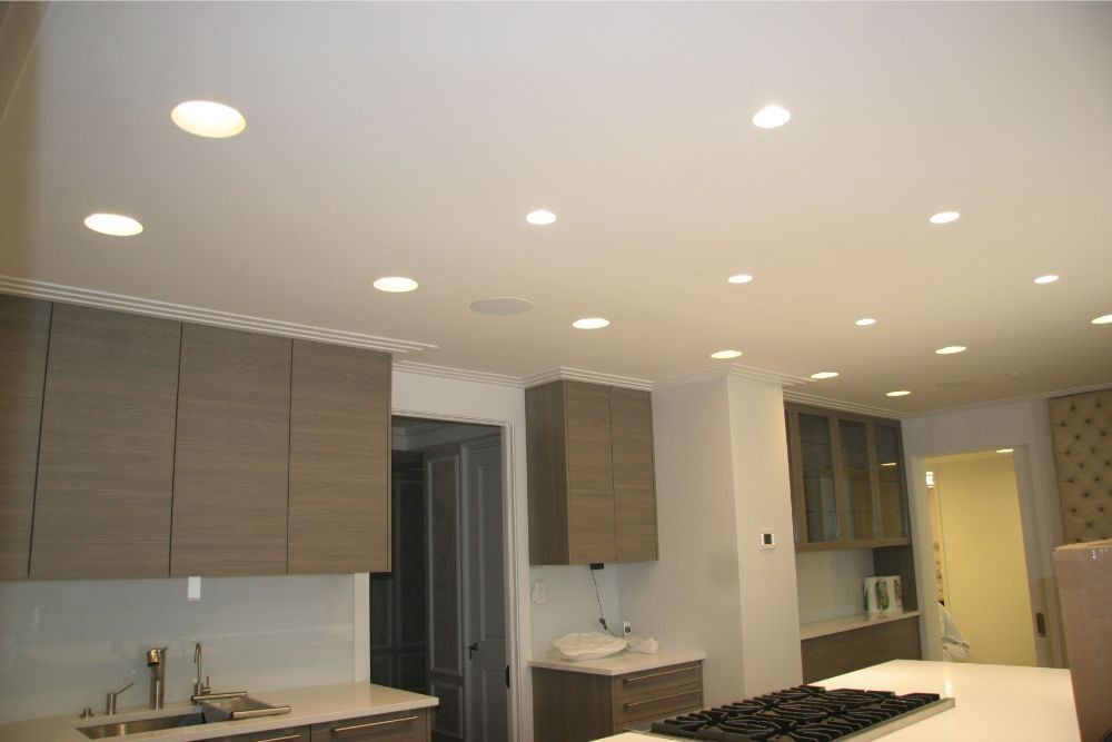 Modern kitchen with wood cabinets, white ceiling, recessed lights, and a large island with cooktop.