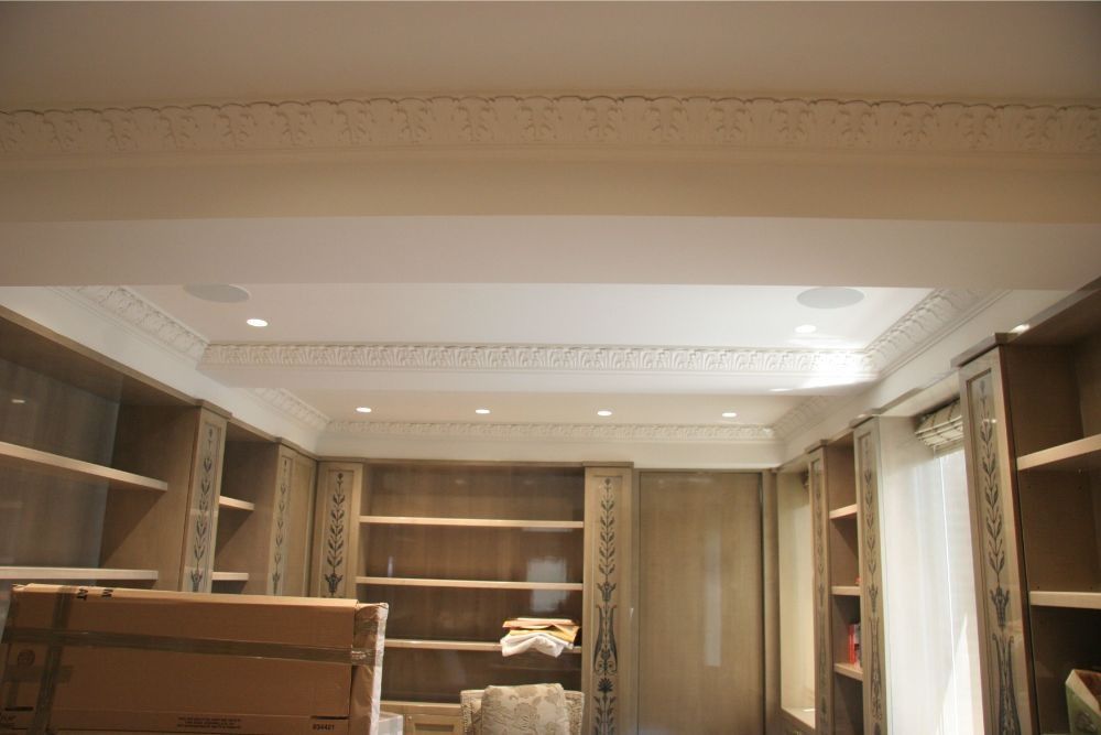 Elegant built-in wooden shelving and cabinets in a softly lit room with ornate ceiling detail
