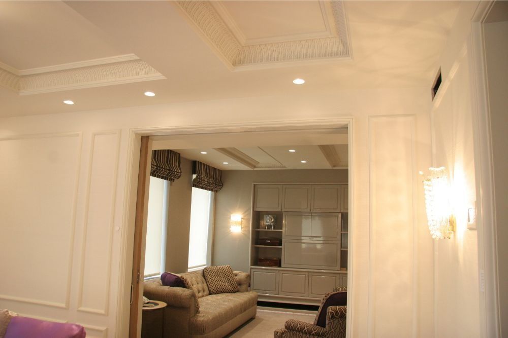 Elegant cream-toned living room with recessed lights, sofa, and large doorway to a second seating area