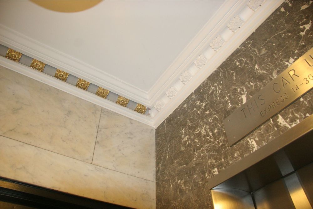 Decorative indoor ceiling and wall corner with gold accents and marble-like panels