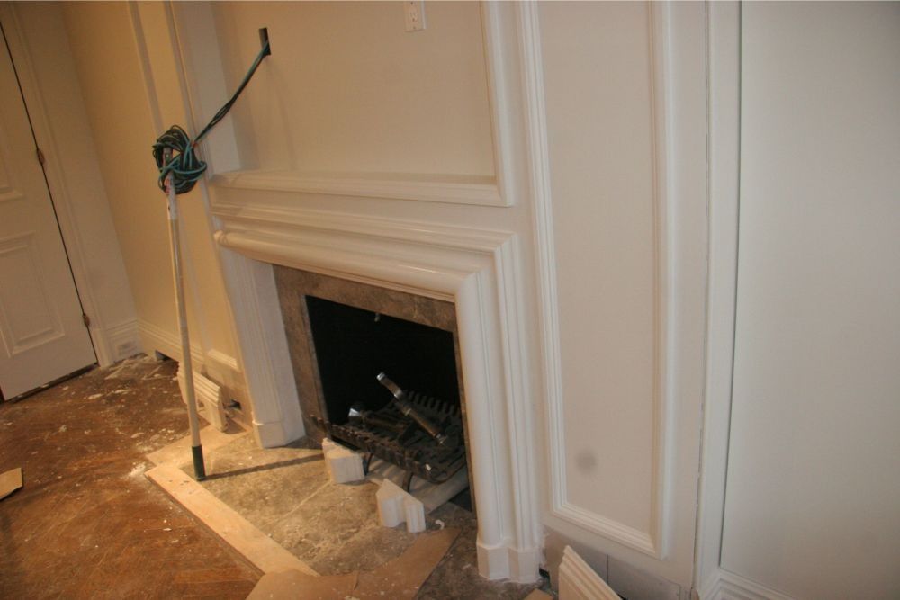 Damaged fireplace with tools and debris in a room under renovation