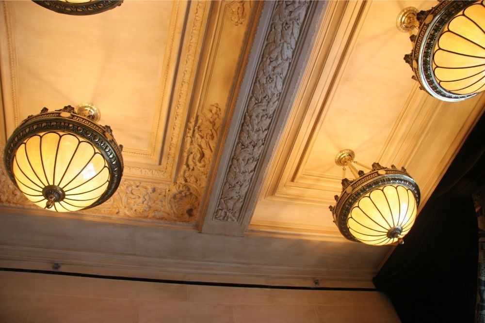 Ornate ceiling with three warm-lit antique pendant lamps in a grand interior