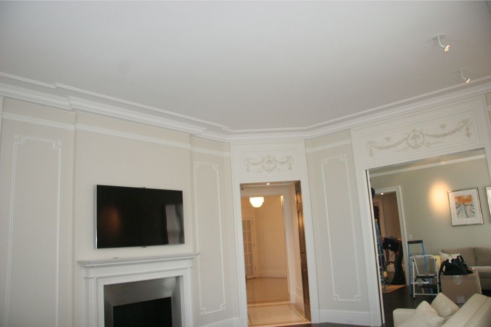 Elegant white living room with fireplace, wall-mounted TV, and doorway to a hallway