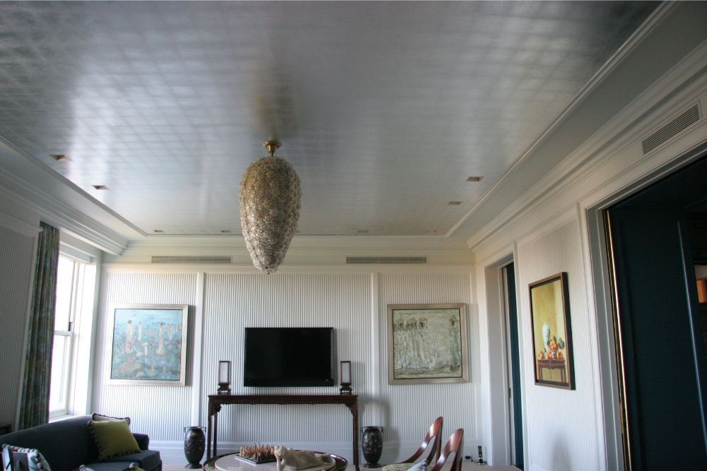 Bright living room with striped walls, TV on fireplace mantel, chandelier, sofa, and framed art