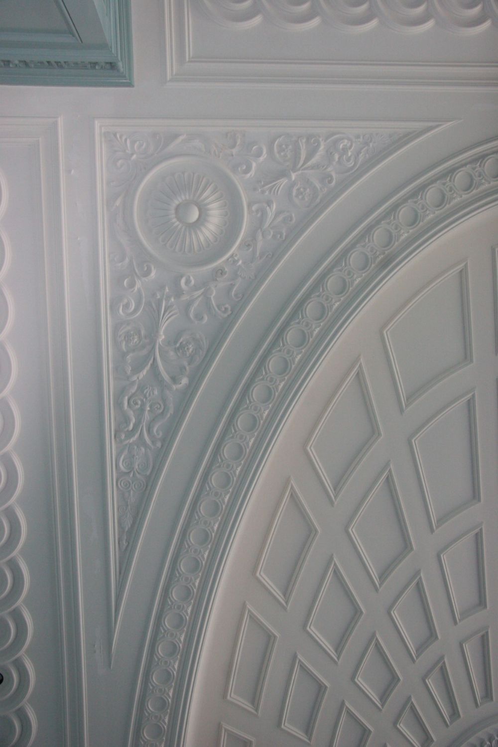 White decorative plaster ceiling with ornate circular and arched embossed patterns