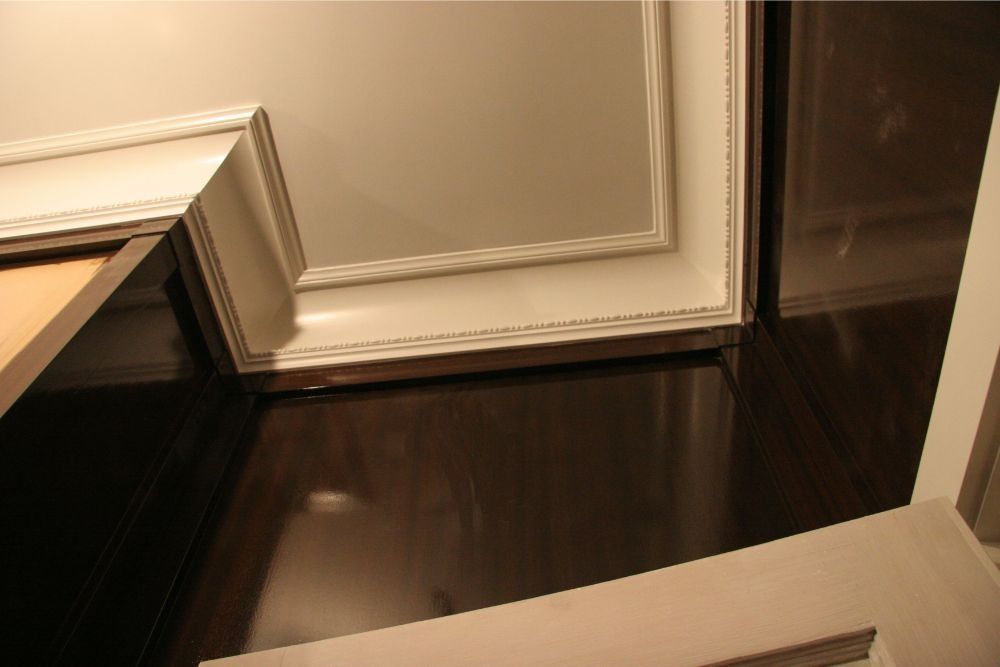 Dark wood floor with white trim molding and an open doorway or panel at the left edge