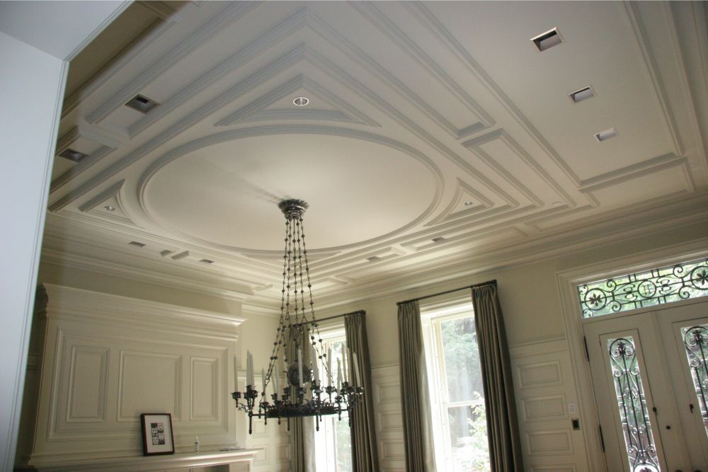 Elegant white ceiling with ornate molding and a central chandelier in a formal room