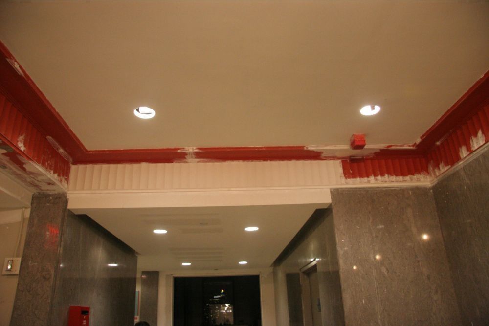Elevator lobby with red trim, beige ceiling, recessed lights, and marble walls