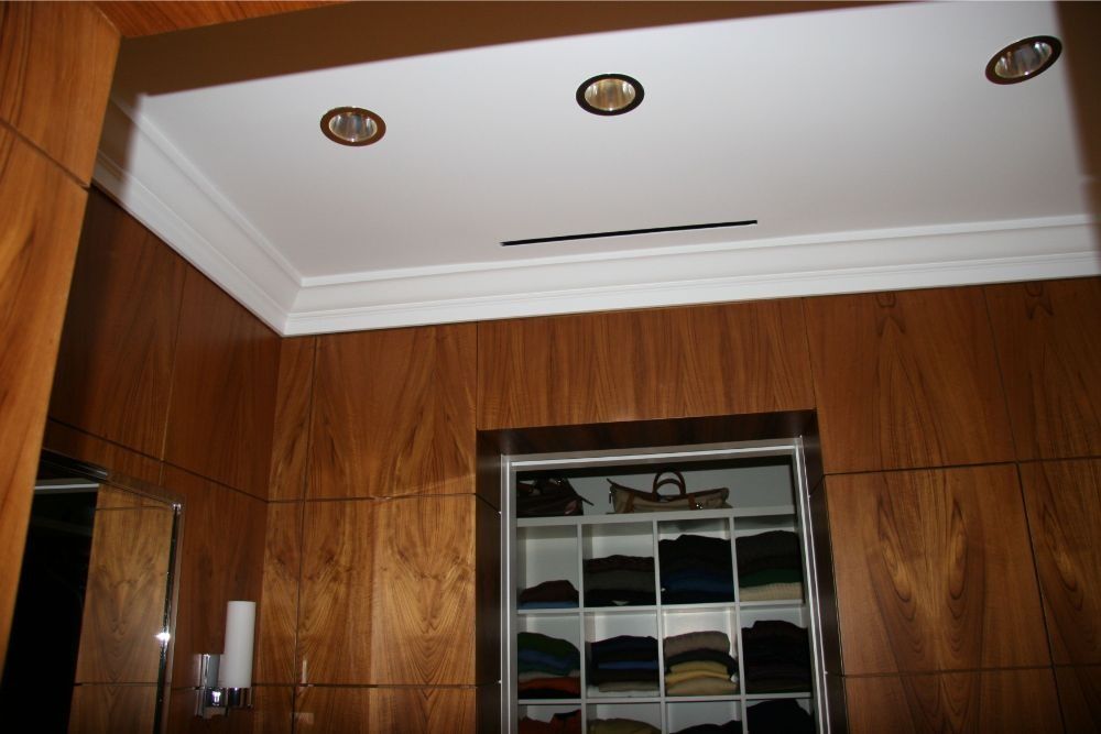 Wood-paneled room with recessed ceiling lights and a mirrored cabinet.