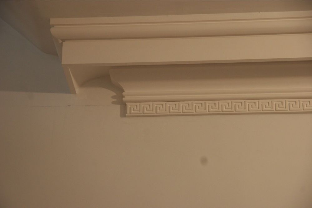 Decorative white crown molding on a beige wall near the ceiling