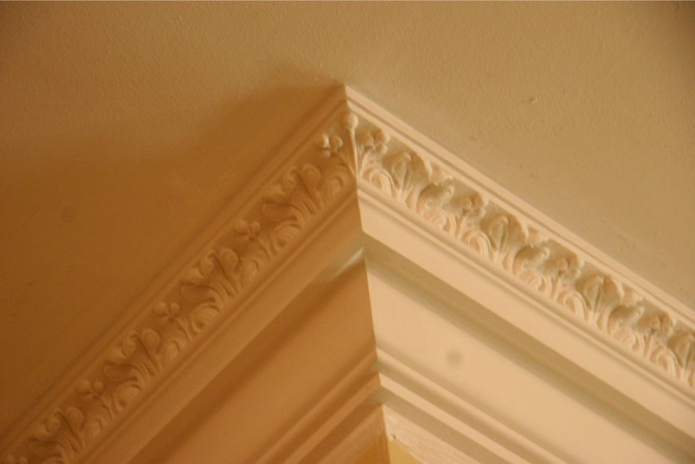 Corner of a cream ceiling with decorative crown molding and warm beige walls.