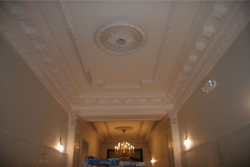 Ornate ceiling with chandelier in a grand hall, viewed from below