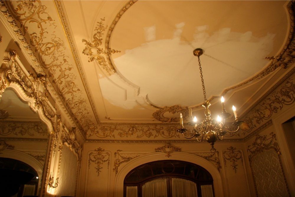 Ornate gilded ceiling and chandelier in a warm-lit historic interior