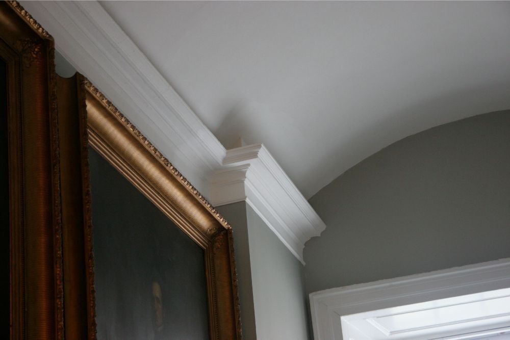 Interior corner with white crown molding, gray wall, and framed artwork edge