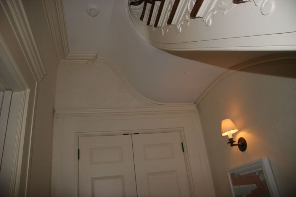 Interior hallway corner with white paneled doors, cream walls, and a lit wall sconce.